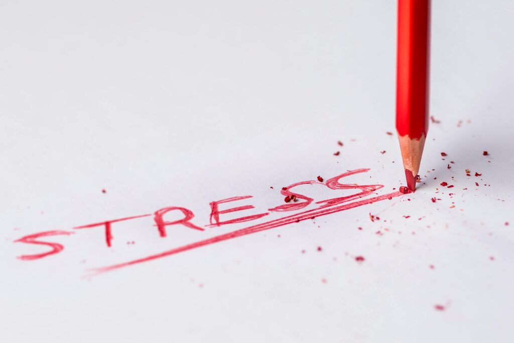 the word stress written in capital letters and red pen on a white page and a red pen next to it