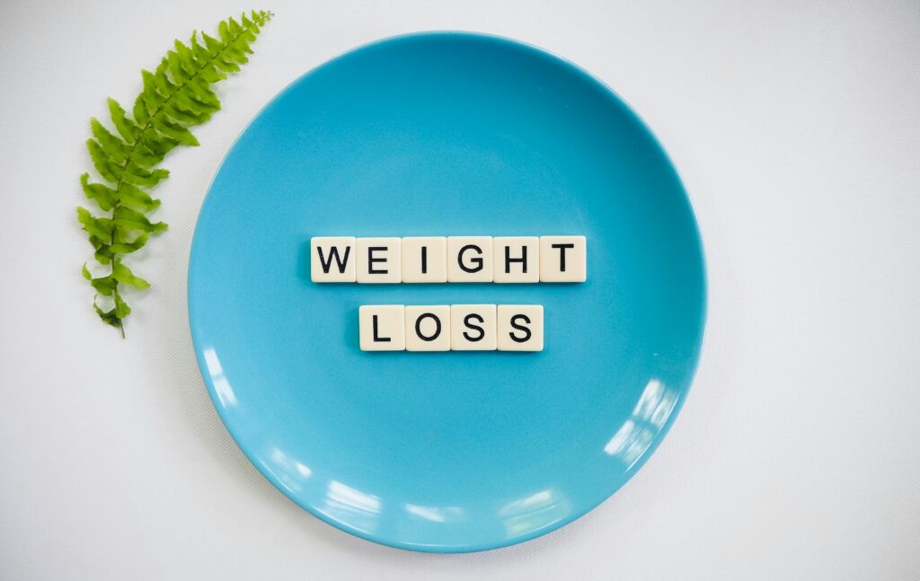 a turquoise empty plate with a weight loss quote written in the middle, a small green tree branch next to the plate