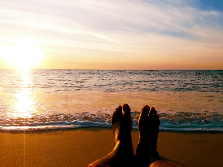 sunset, ocean, and two feet in the sand on the beach