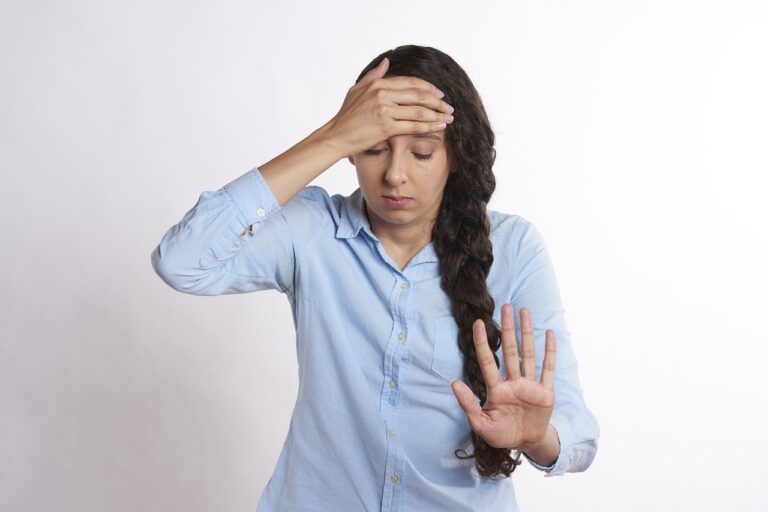 Black haired, blue-shirted woman holding her head with her hand